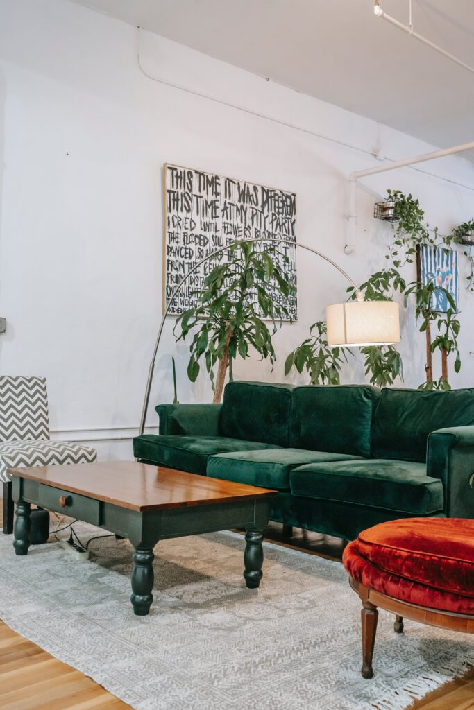 green velvet sofa in lounge with plants and red stool

staging design