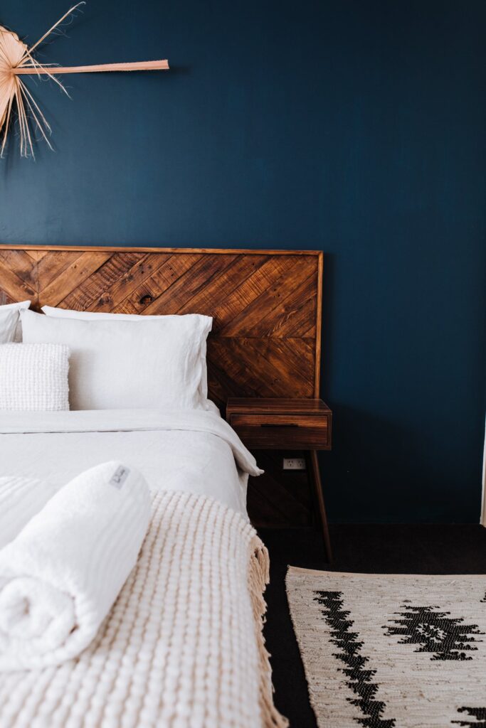 wooden bed frame in blue bedroom with white bed

staging design